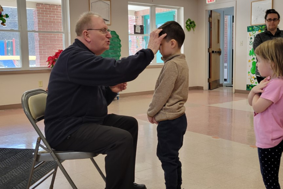 Monsignor Dubois distributes ashes to children at All Saints Catholic School in Bangor. 