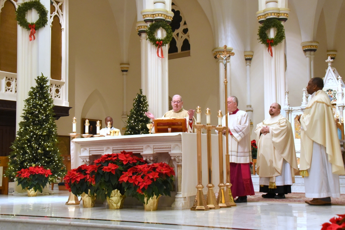 Bishop Deeley celebrating the Liturgy of the Eucharist with several priests beside him.