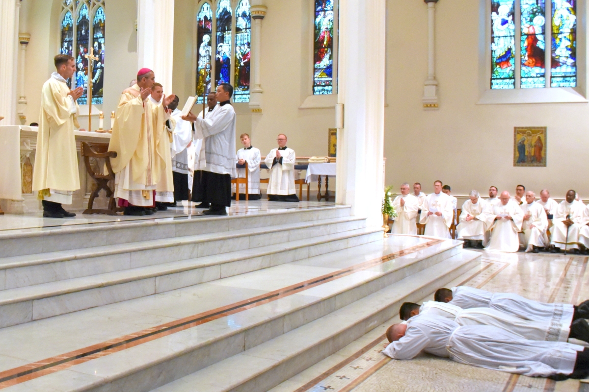 Bishop Ruggieri prays while the three lie prostrate.