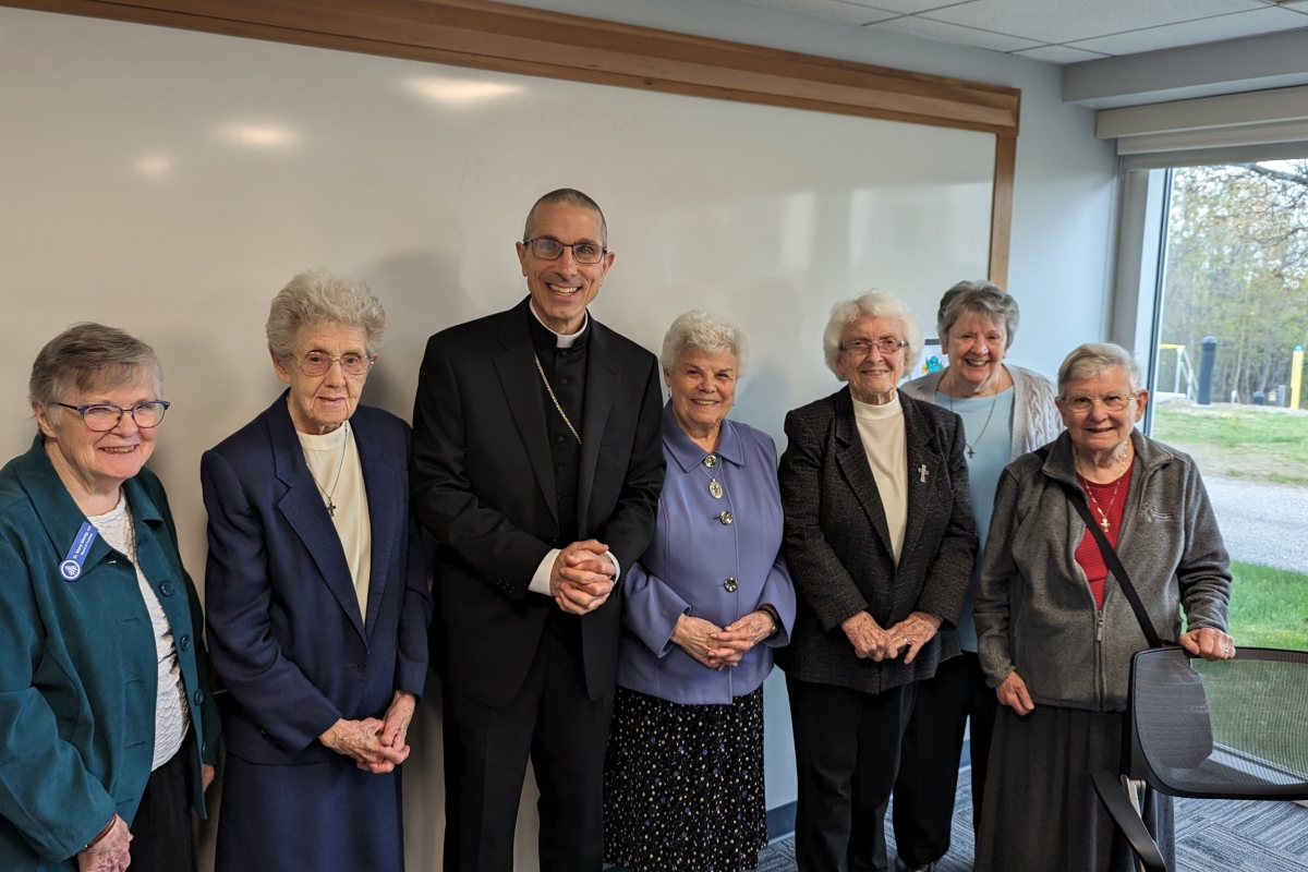 Bishop standing with six nuns