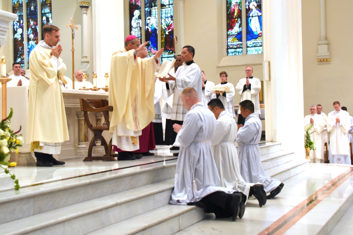Bishop James Ruggieri prays the Prayer of Ordination for Hoa Tien Nguyen, Thanh Duc Pham, and Erin Donlon.