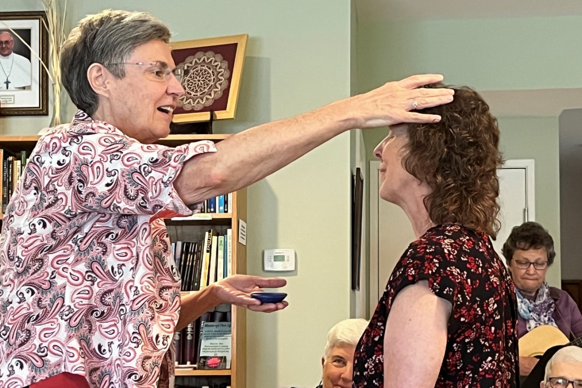 Sister Judy Donovan anoints the head of Toni Fredette.