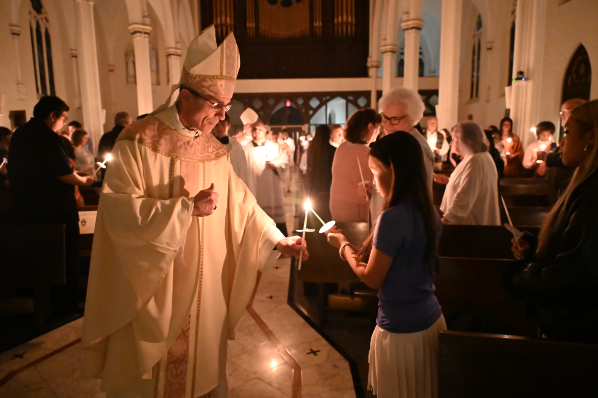 Bishop lights the candle for a young woman.