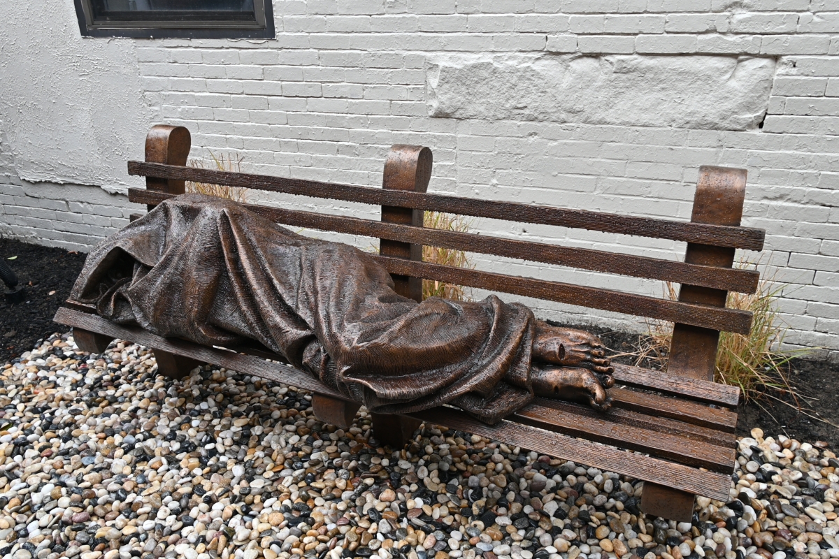 sculpture of mass sleeping on a bench
