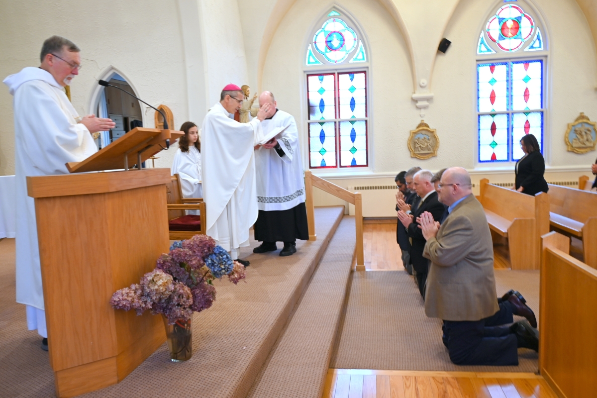 Bishop Ruggieri prays over the kneeling deacon candidates.